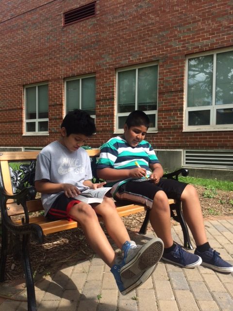 two students sitting on a bench reading