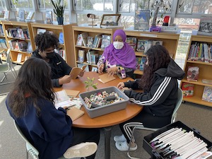 alunos na mesa da biblioteca com bibliotecário