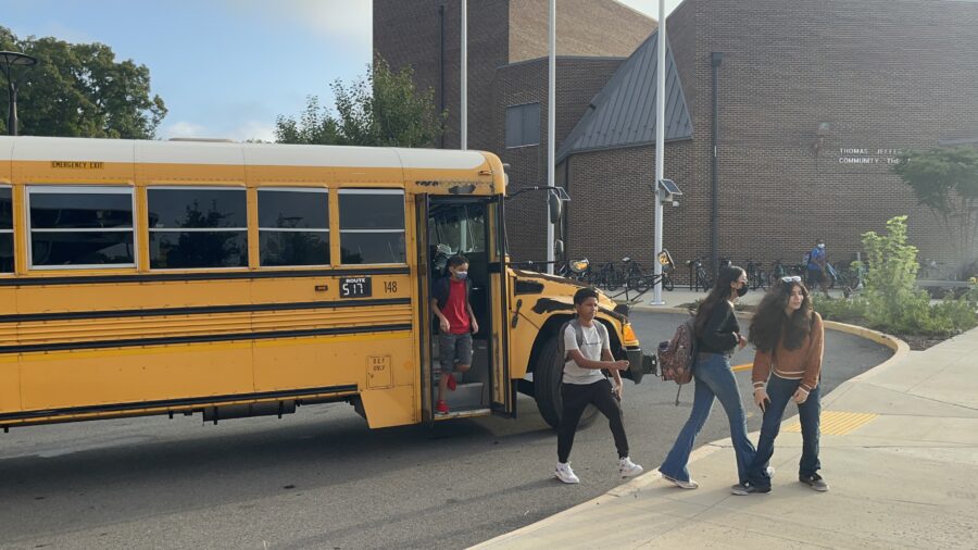 学校の初日にバスを降りる生徒たち