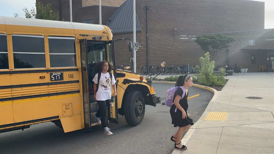学校の初日にバスを降りる生徒たち