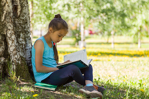 menina sentada do lado de fora lendo
