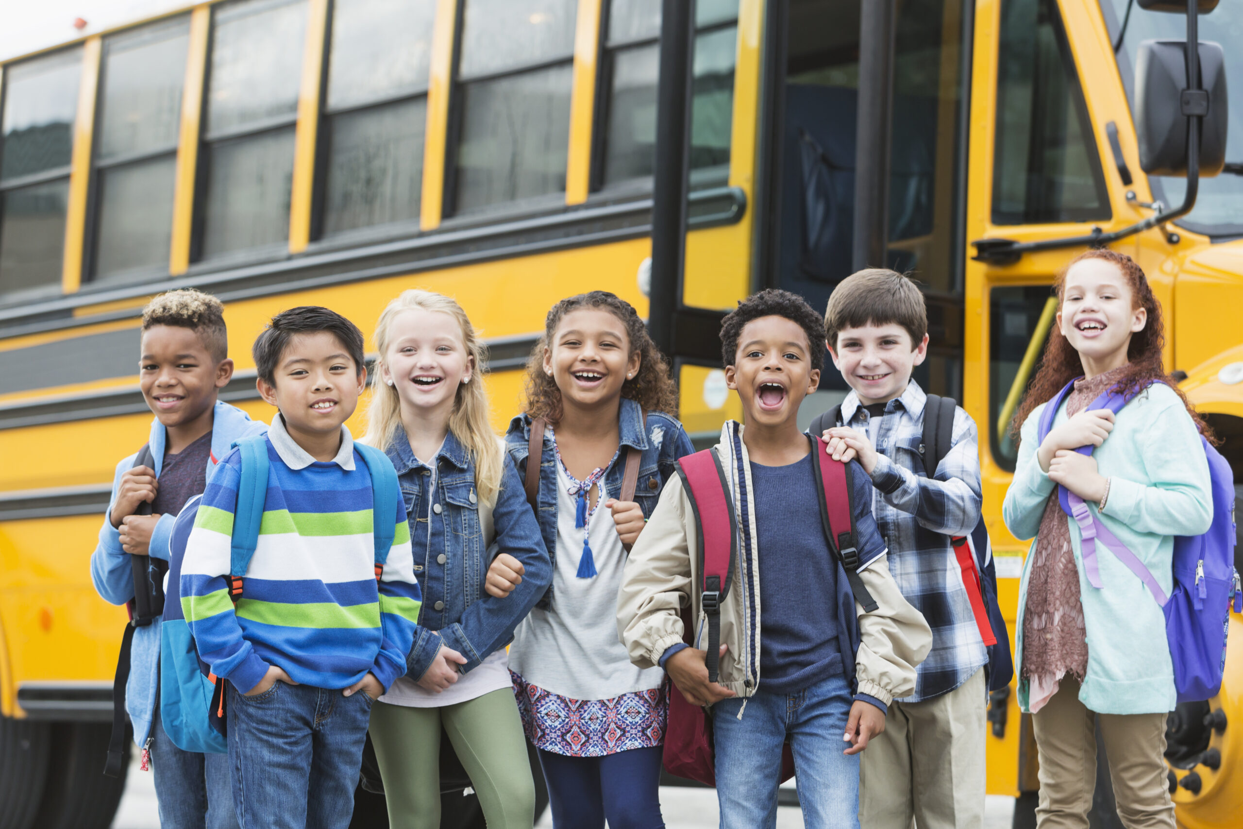 Elementary school children waiting outside bus