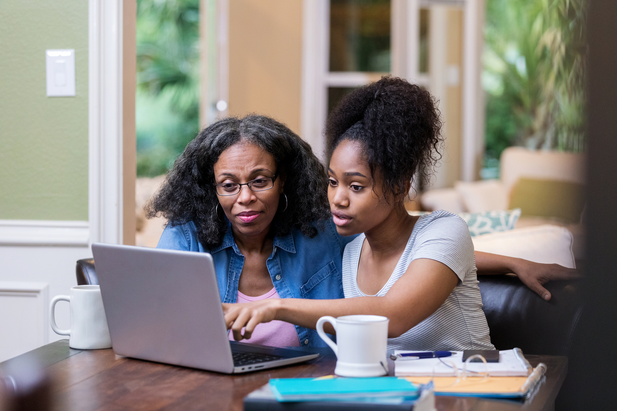 teen showing mother something on computer