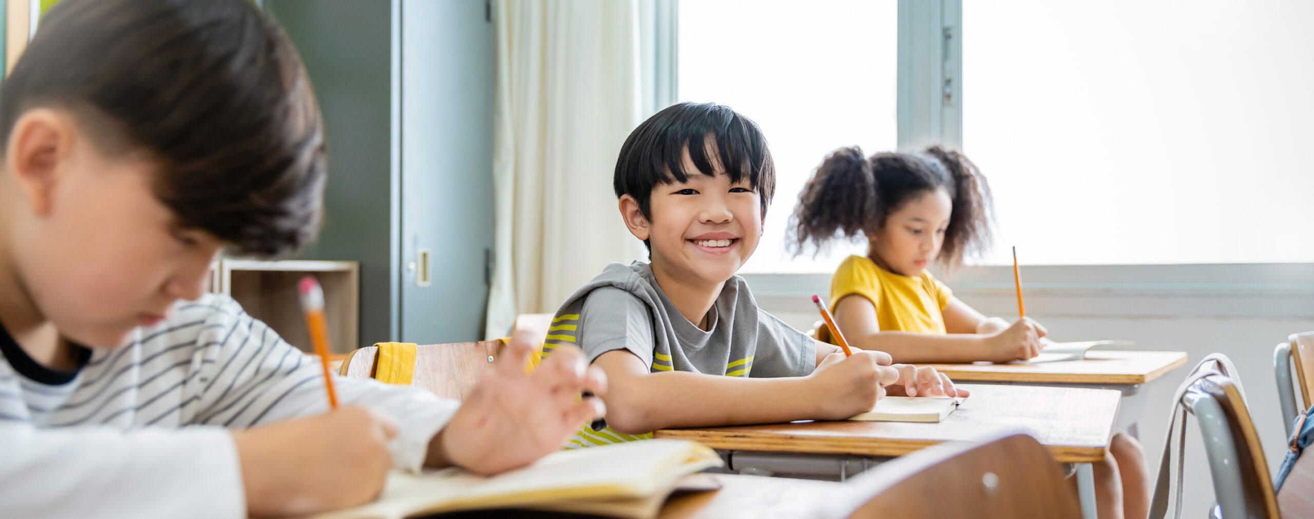 student writing at desk in classroom at elementary school