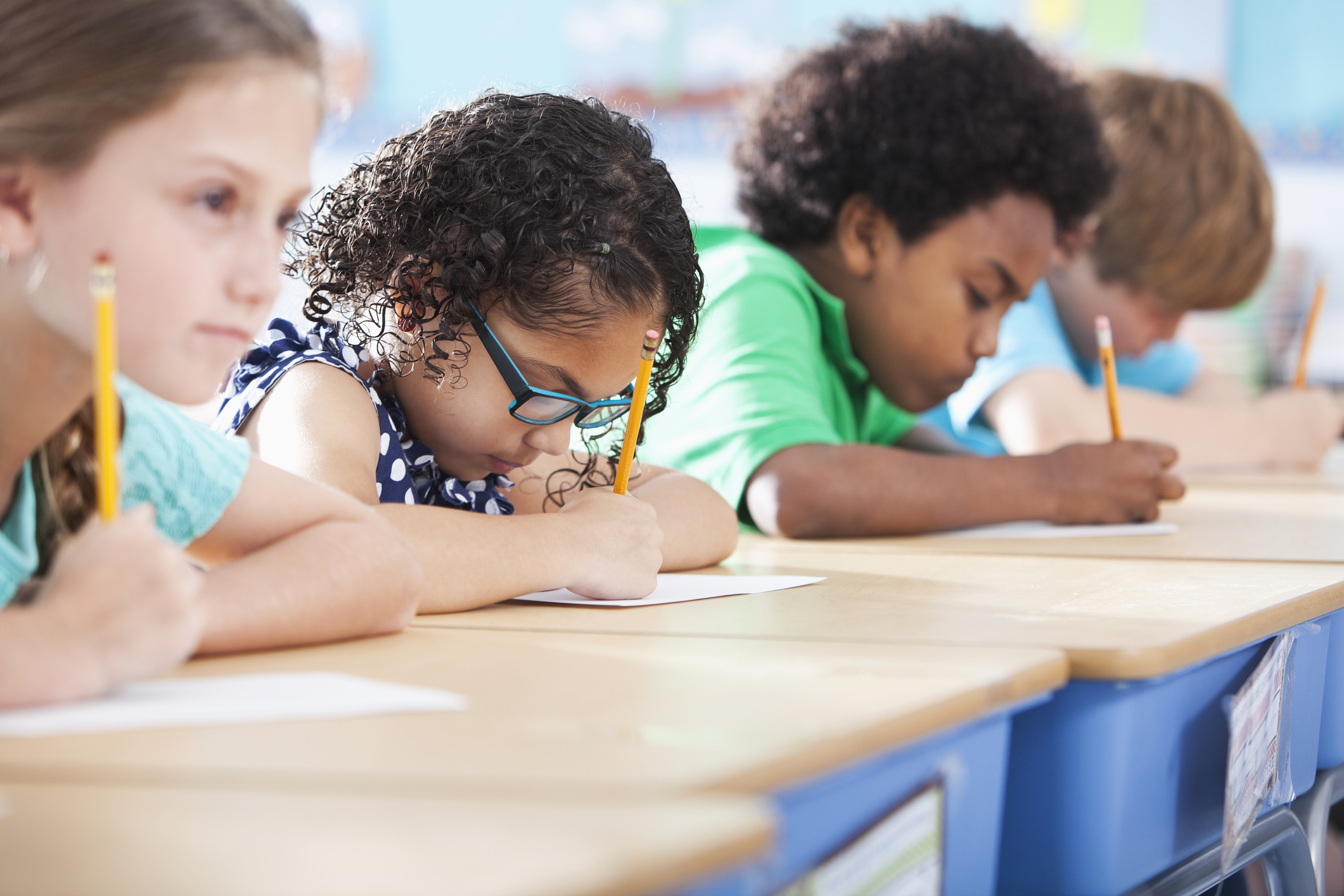 Multi-ethnic elementary school children writing in classroom.