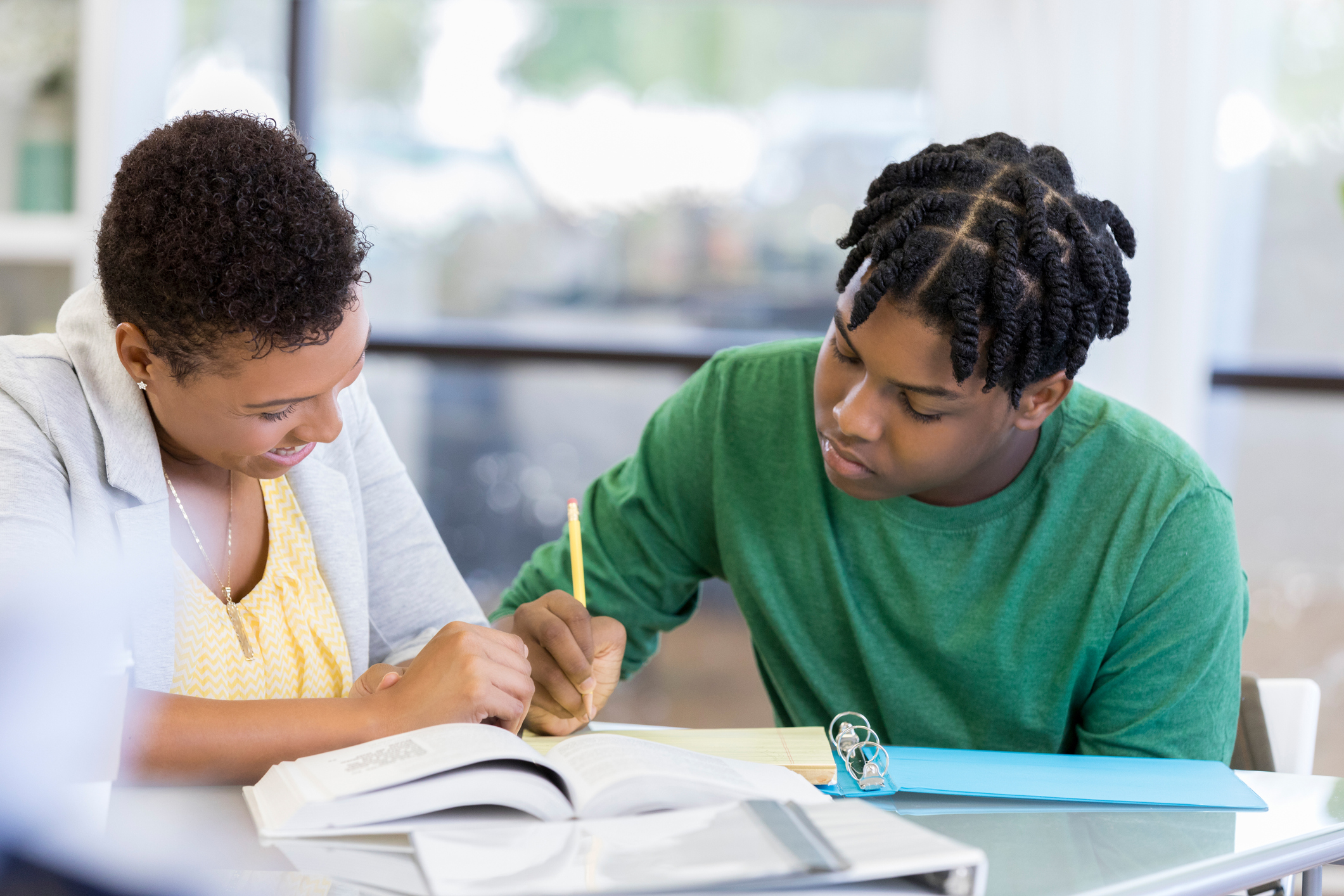 Teenage boy works on homework with tutor