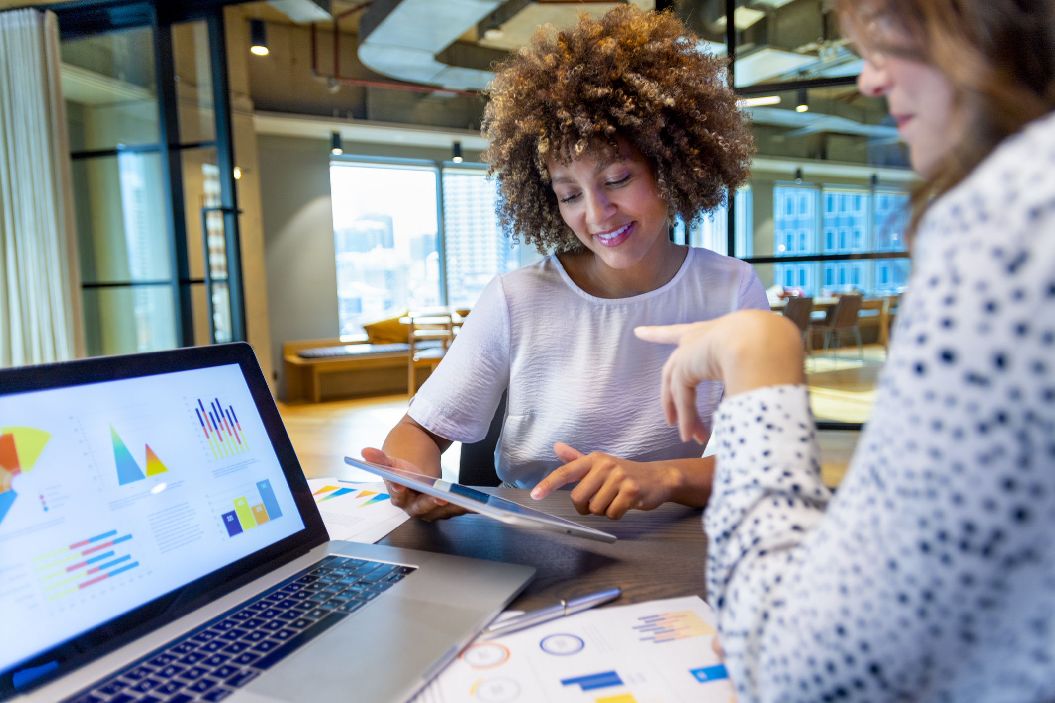 two women discussing finance charts and graphs on a laptop