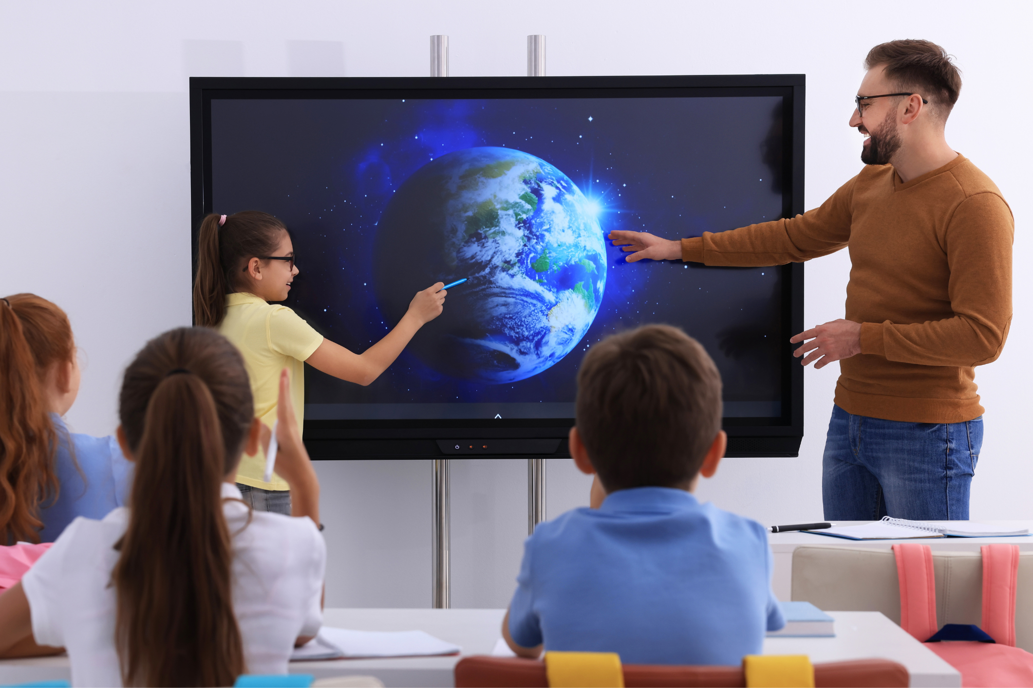 Teacher and student standing at a digital board