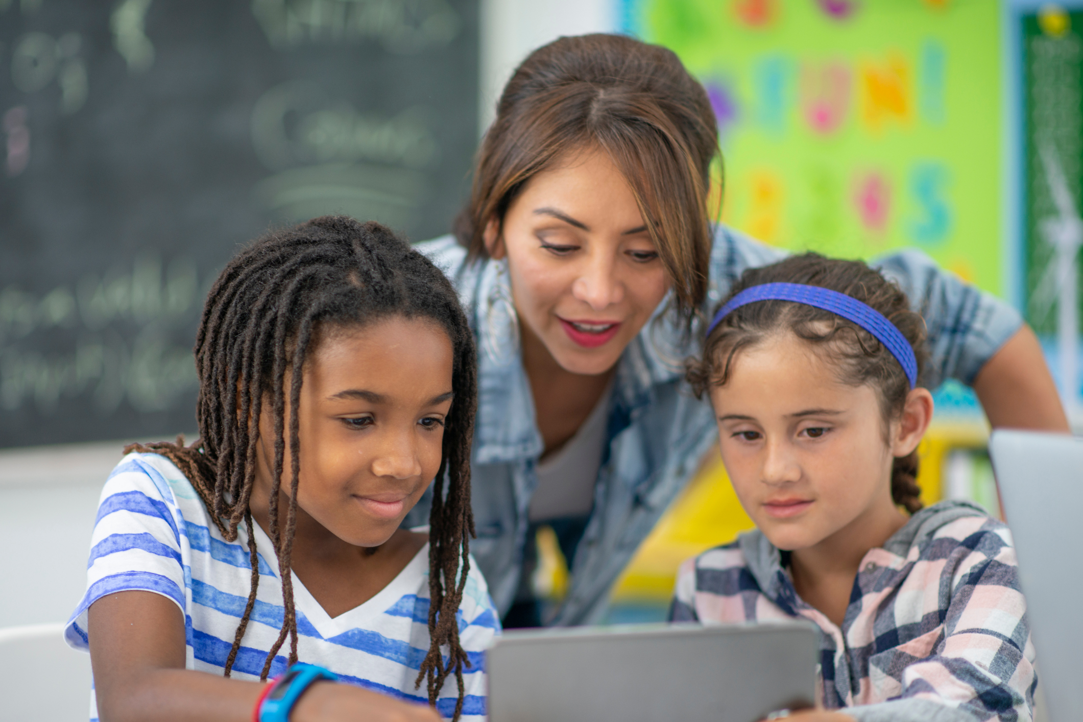 A teacher working with two students on a laptop