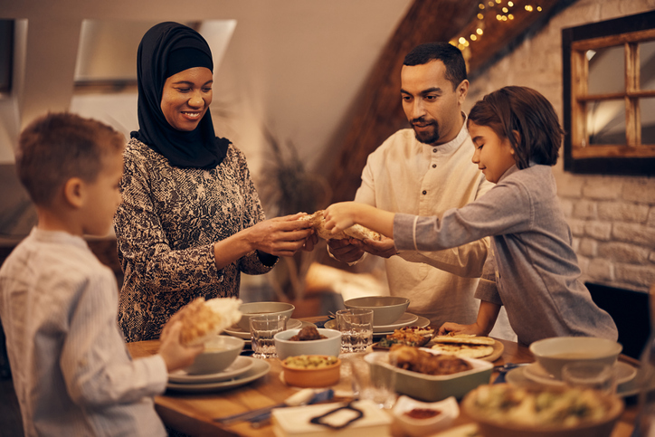 Middle Eastern family sharing pita bread at dining table on Ramadan.