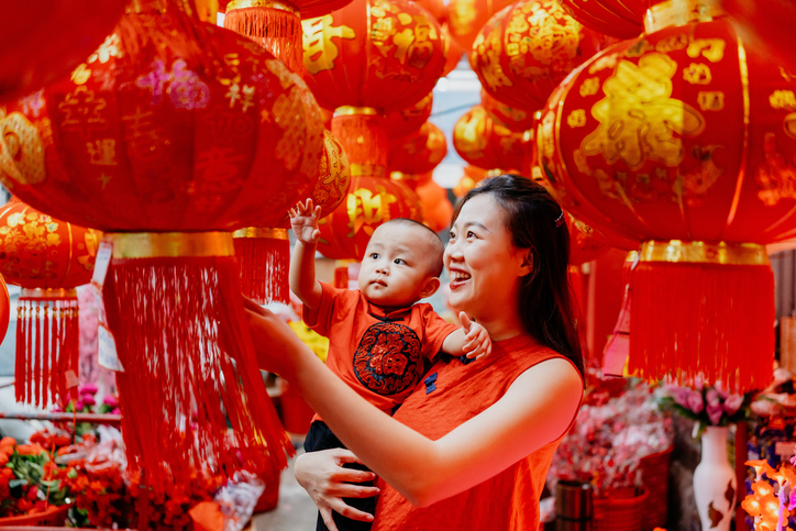 Asian Chinese mother carrying her baby and looking at red lantern for Chinese new year